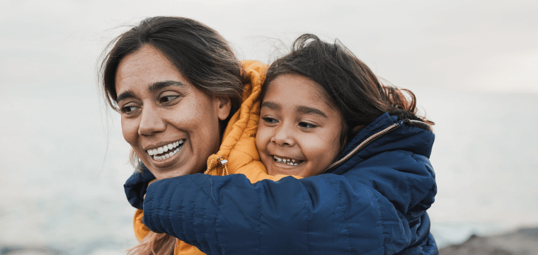 Image of a hispanic woman carrying a child on her back. Depicting Lifebit's advanced technology used in its precision medicine platform and patient registry