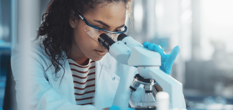 Image of a female scientist looking through a microscope depicting Lifebit's expertise in biomedical research through its Patient Registry and Federated Data Analytics